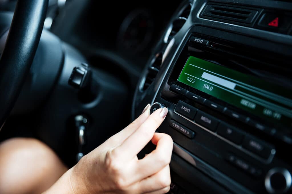 Cropped image of a woman hand turning button of radio in car