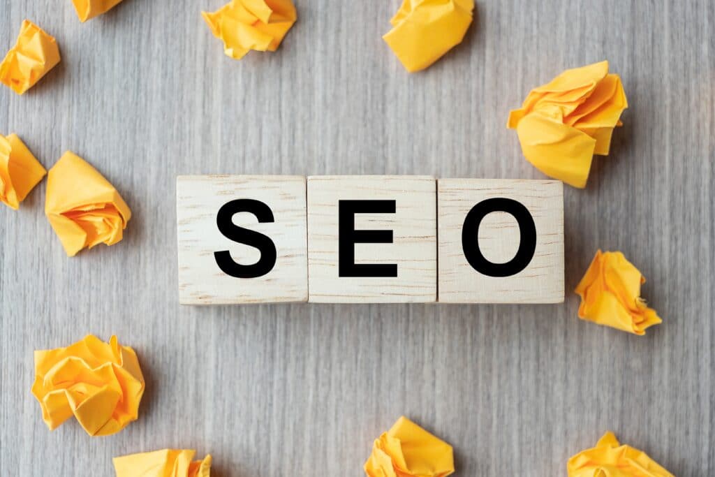 SEO (Search Engine Optimization) text wood cubes with crumbled paper on wooden table background. Idea, Vision, Strategy, Analysis, Keyword and Content concept