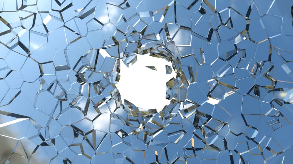 Sharp pieces of blue shattered glass and hole on white