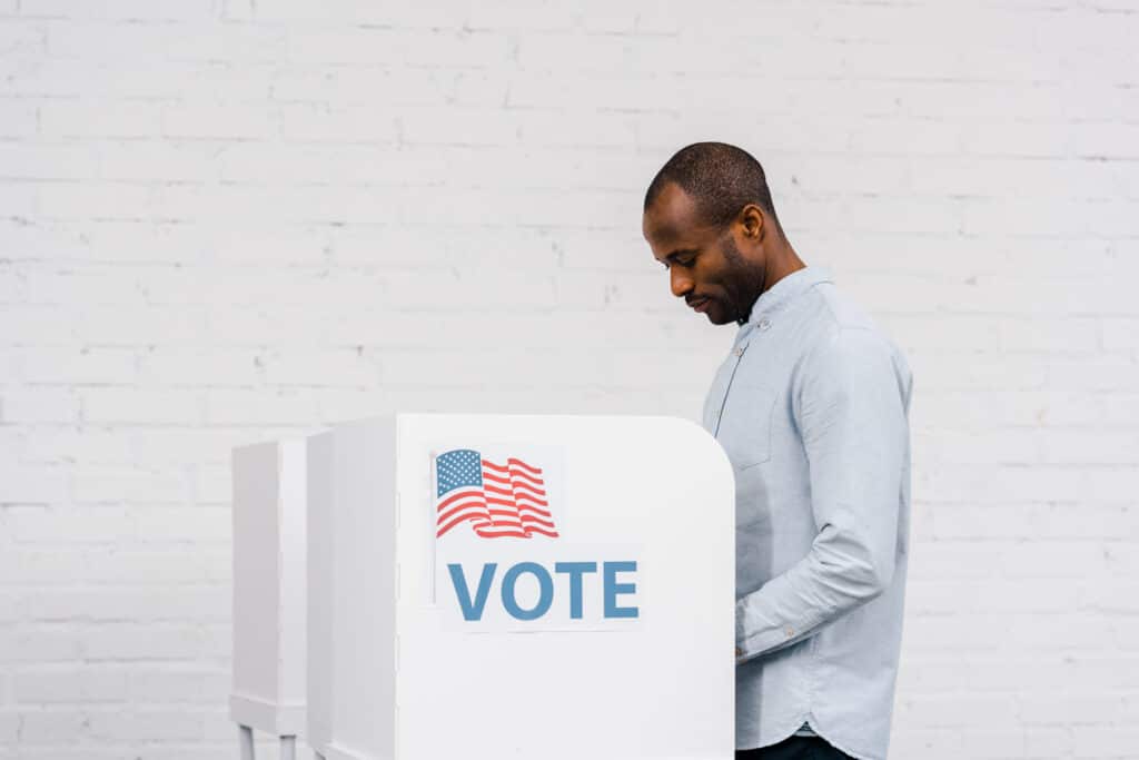 african american citizen voting near stand with vote lettering
